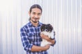 Portrait of a handsome Asian man with long hair wearing a blue checkered shirt and jeans. Hold his Pomeranian and play with it Royalty Free Stock Photo