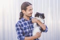 Portrait of a handsome Asian man with long hair wearing a blue checkered shirt and jeans. Hold his Pomeranian and play with it Royalty Free Stock Photo