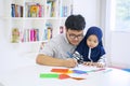 Man teaching his cute muslim daughter how to draw