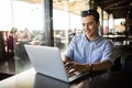 Portrait of handsome asian smiling man using laptop in the cafe . Freelance work Royalty Free Stock Photo