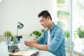 Portrait of handsome asian young business man holding mobile phone and working on laptop computer at office desk Royalty Free Stock Photo