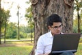 Portrait of handsome asian young man working on laptop computer in city park. Royalty Free Stock Photo