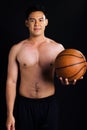 Portrait of handsome asian young muscular man smiling with confidence, standing and holding basketball on isolated black Royalty Free Stock Photo