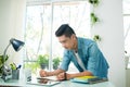 Portrait of handsome asian young writing something on notebook a