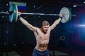 Portrait of a handsome athlete . Athlete raises the barbell over your head. shots in the dark tone. Cross style fit Royalty Free Stock Photo