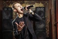 Portrait of handsome attractive singer singing hit with open mouth in microphone gesticulating with hand
