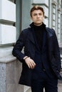 Portrait of a handsome, attractive, young man in a blue suit, coat, in the city. pensive and sad, waiting Royalty Free Stock Photo