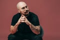 Portrait of handsome bald bearded man with moustache in glasses who sitting on chair in studio Royalty Free Stock Photo