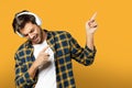 Portrait of handsome beard guy in white t-shirt and plaid shirt listening to music in headphones singing Royalty Free Stock Photo