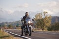 Bearded biker in black leather jacket on modern motorcycle on country roadside.