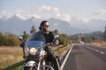 Bearded biker in black leather jacket on modern motorcycle on country roadside. Royalty Free Stock Photo