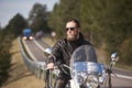 Bearded biker with long hair in black leather jacket sitting on modern motorcycle. Royalty Free Stock Photo