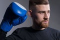 Portrait of handsome bearded brutal guy in sportswear standing in a combat pose, holding raised hands near his face, in boxing