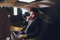 Portrait of handsome bearded businessman speaking by phone sitting in back seat of car. Royalty Free Stock Photo