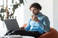 Business man using pc sitting on chair drinking coffee