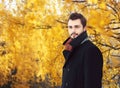 Portrait of handsome bearded man wearing a black coat in autumn