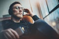 Portrait handsome bearded man wearing glasses,headphones listening to music at modern home.Guy sitting in vintage chair Royalty Free Stock Photo