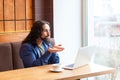 Portrait of handsome bearded romantic young adult man freelancer in casual style sitting in cafe and chating with his friend in Royalty Free Stock Photo