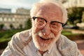 Portrait of handsome bearded senior man in glasses looking at camera and smiling while standing outdoors on a sunny day Royalty Free Stock Photo