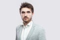 Portrait of handsome bearded serious man with brown hairs and beard in white shirt and casual grey suit standing and looking at