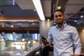 Portrait of handsome black African businessman inside shopping mall smiling and holding mobile phone Royalty Free Stock Photo