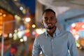 Portrait of handsome black African businessman outdoors in city at night smiling and looking at camera Royalty Free Stock Photo