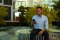 Portrait of handsome black African businessman sitting outdoors in city at night while using mobile phone Royalty Free Stock Photo