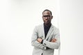 Handsome black businessman with glasses leaning against white wall Royalty Free Stock Photo