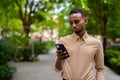 Portrait of handsome black young African businessman using phone outdoors at park Royalty Free Stock Photo