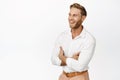 Portrait of handsome blond adult man, strong guy in white shirt, cross arms on chest, laughing and smiling while looking Royalty Free Stock Photo