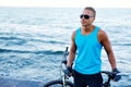 Portrait of a handsome blond athletic man with bicycle outdoors on the beach. Royalty Free Stock Photo