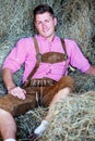 Handsome blond bavarian man sitting in hay Royalty Free Stock Photo
