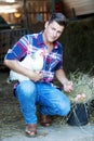 Handsome blond man holding a white chicken with a basket of eggs