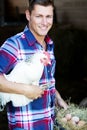 Handsome blond man holding a white chicken with a basket of eggs