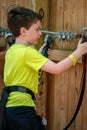 Portrait of a handsome boy on a rope park among trees. Children summer activities.