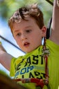 Portrait of a handsome boy on a rope park among trees. Children summer activities.