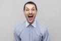 Portrait of handsome bristle businessman in classic light blue shirt standing with open mouth, screaming and looking at camera Royalty Free Stock Photo