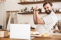 Portrait of handsome brunette man using laptop while making homemade pasta in kitchen at home Royalty Free Stock Photo