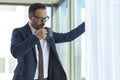 Portrait of handsome businessman drinking coffee and admire the view standing by the window in office. Attractive boss enjoying Royalty Free Stock Photo