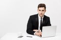 Portrait of a handsome businessman holding smartphone while working on a computer at his desk. He is in a office his Royalty Free Stock Photo