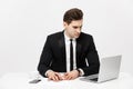 Portrait of a handsome businessman holding smartphone while working on a computer at his desk. He is in a office his Royalty Free Stock Photo