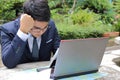 Portrait of handsome businessman looking at laptop and thinking about his job in the park outdoors Royalty Free Stock Photo