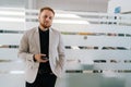 Portrait of handsome businessman in suit holding using mobile phone standing in light hallway corridor of modern Royalty Free Stock Photo