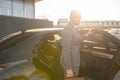 Portrait of a handsome businessman in sunglasses standing near the car outdoors in front of the modern building facade Royalty Free Stock Photo