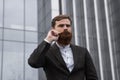 Portrait of an handsome businessman wearing jacket over office building in financial district outdoors. Young bearded Royalty Free Stock Photo