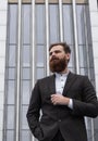 Portrait of an handsome businessman wearing jacket over office building in financial district outdoors. Young bearded Royalty Free Stock Photo