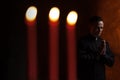 Portrait of handsome catholic priest or pastor with dog collar, dark red background.