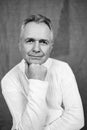 Portrait of handsome Caucasian senior man with grey hair against gray background in black and white Royalty Free Stock Photo