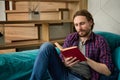 Portrait of a handsome charming bearded middle aged Caucasian man reading book, sitting on sofa at home interior, enjoying a Royalty Free Stock Photo