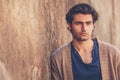 Portrait of handsome and charming young man. He is leaning against an outdoor wall.